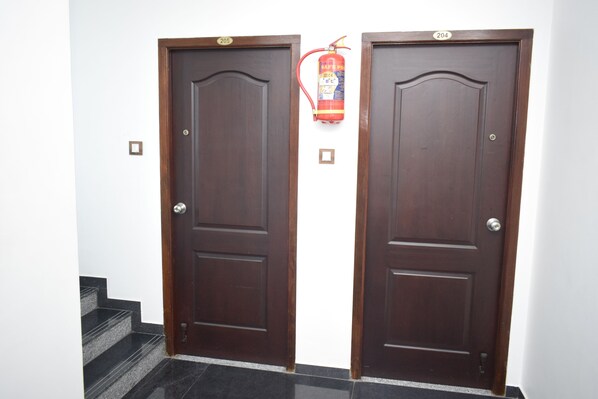 Dos puertas de madera con un extintor instalado entre ellas.