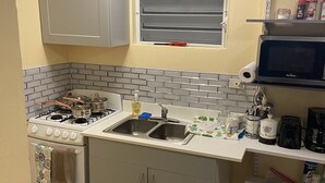 A compact kitchen with a gas stove, double sink, and a microwave.