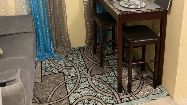 A compact living space with a dining table, chairs, a TV, and a small kitchen area.