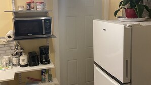A compact kitchen with a microwave, coffee maker, and a white refrigerator.