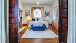 A bedroom with a large bed, a bench, a chandelier, and artwork on the walls. - New Renovated 2BR Highland Home Hot Tub Playground (Louisville)