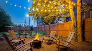 A backyard with a fire pit, wooden chairs, and string lights. - New Renovated 2BR Highland Home Hot Tub Playground (Louisville)