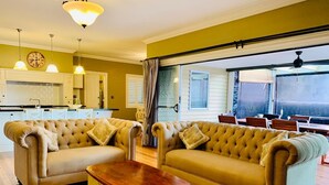 Una sala de estar con dos sofás capitonados, un aparador de madera y un comedor con mesa y sillas.