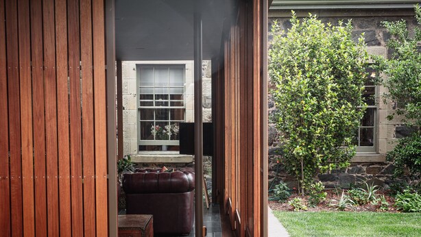 A wooden door leading to a stone-walled room with a bench and a table. - Fusilier Cottage Battery Point (Battery Point)