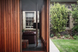 Puerta de madera que da a una habitación con paredes de piedra, una banca y una mesa.
