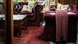 A cozy room with a leather sofa, a wooden coffee table, and a red patterned rug. - Fusilier Cottage Battery Point (Battery Point)