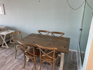 A dining area with a wooden table and chairs, a small white table, and a light blue wall.