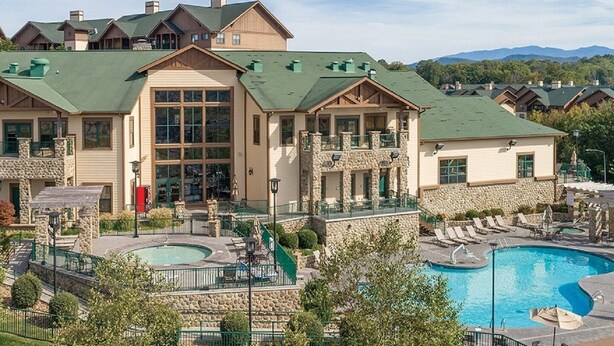 A resort with multiple buildings, a central pool area, and a mountain backdrop. - Great Smokey Mountains Resort - Pigeon Forts Condo  (Pigeon Forge)