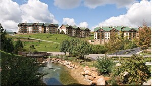 A hotel with multiple buildings, a landscaped area with a pond, and a road. - Great Smokey Mountains Resort - Pigeon Forts Condo  (Pigeon Forge)