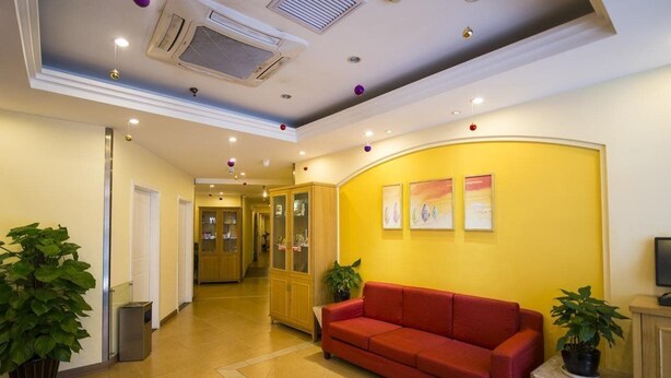 A hotel lobby with a red sofa, potted plants, and framed artwork on the wall. - Home Inn Hotel Beijing Tongzhou Xinhua South Road (Tongzhou)