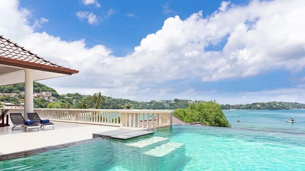 A clear blue pool with a view of the sea and a covered area with lounge chairs. - Luxury Beachfront Tai Pan Villa (Wichit)