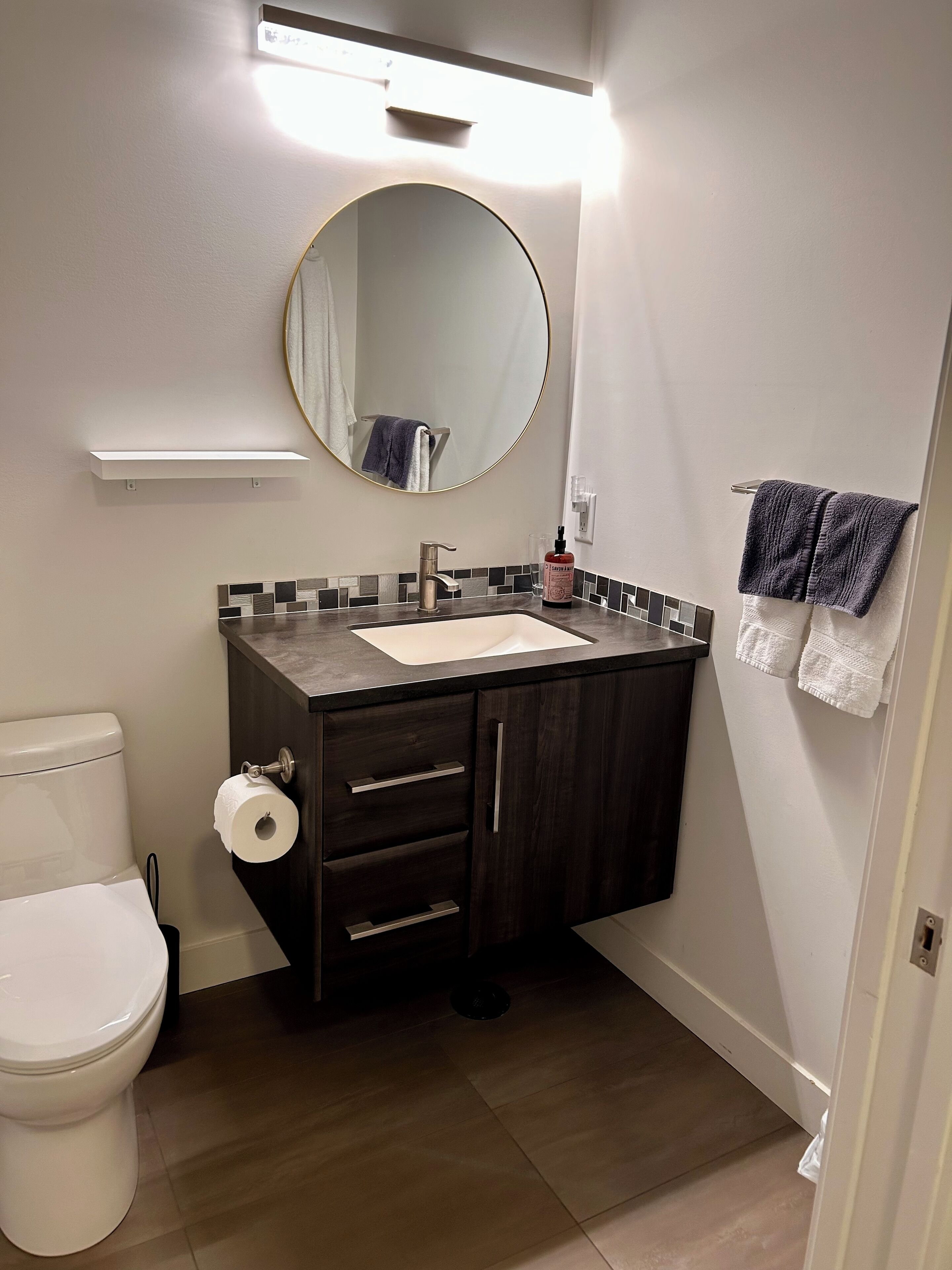 A modern bathroom with a toilet, sink, and mirror.