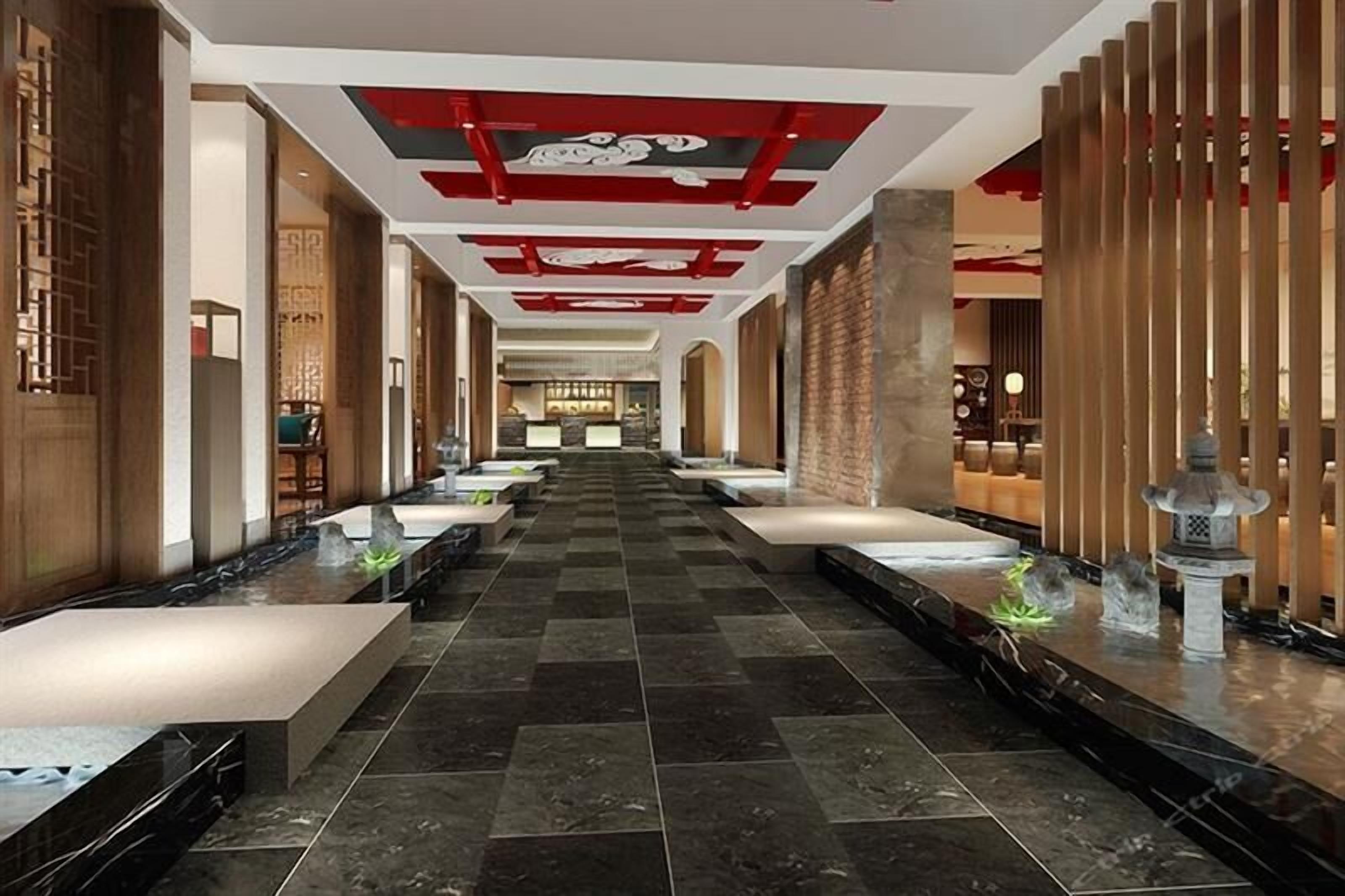 A hotel lobby with a long corridor, seating areas, and a decorative ceiling.