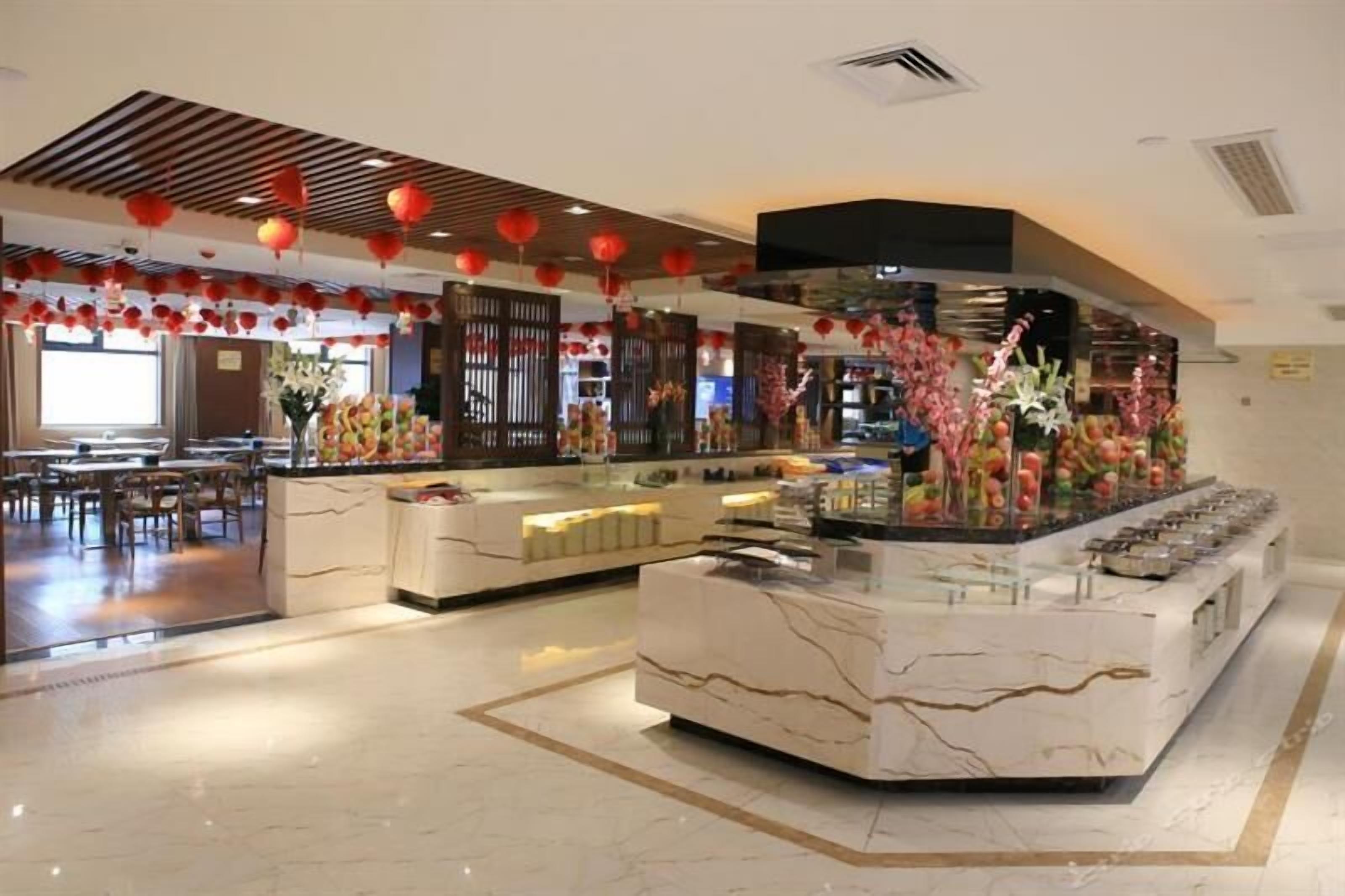 A modern restaurant with a marble counter, red lanterns, and a variety of food displays.