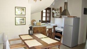 Una cocina con armarios de madera, una estufa, un fregadero y un refrigerador. Hay dos cuadros en la pared.