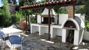 Un patio al aire libre con piso de piedra, una mesa blanca y una silla azul.