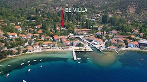 Vista aérea de El Villa, con un diseño costero que muestra edificios, un puerto deportivo y aguas azules cristalinas.