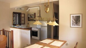 Una cocina con una mesa de comedor, una araña y un refrigerador.