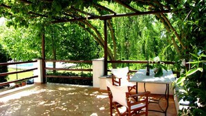 Eine Außenpatio mit Tisch und Stühlen, umgeben von üppiger Vegetation und Blick auf einen Swimmingpool.