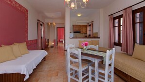 Ein Hotelzimmer mit Bett, Esstisch mit Stühlen, einer Küchenzeile und einem Wohnbereich mit einer Couch.