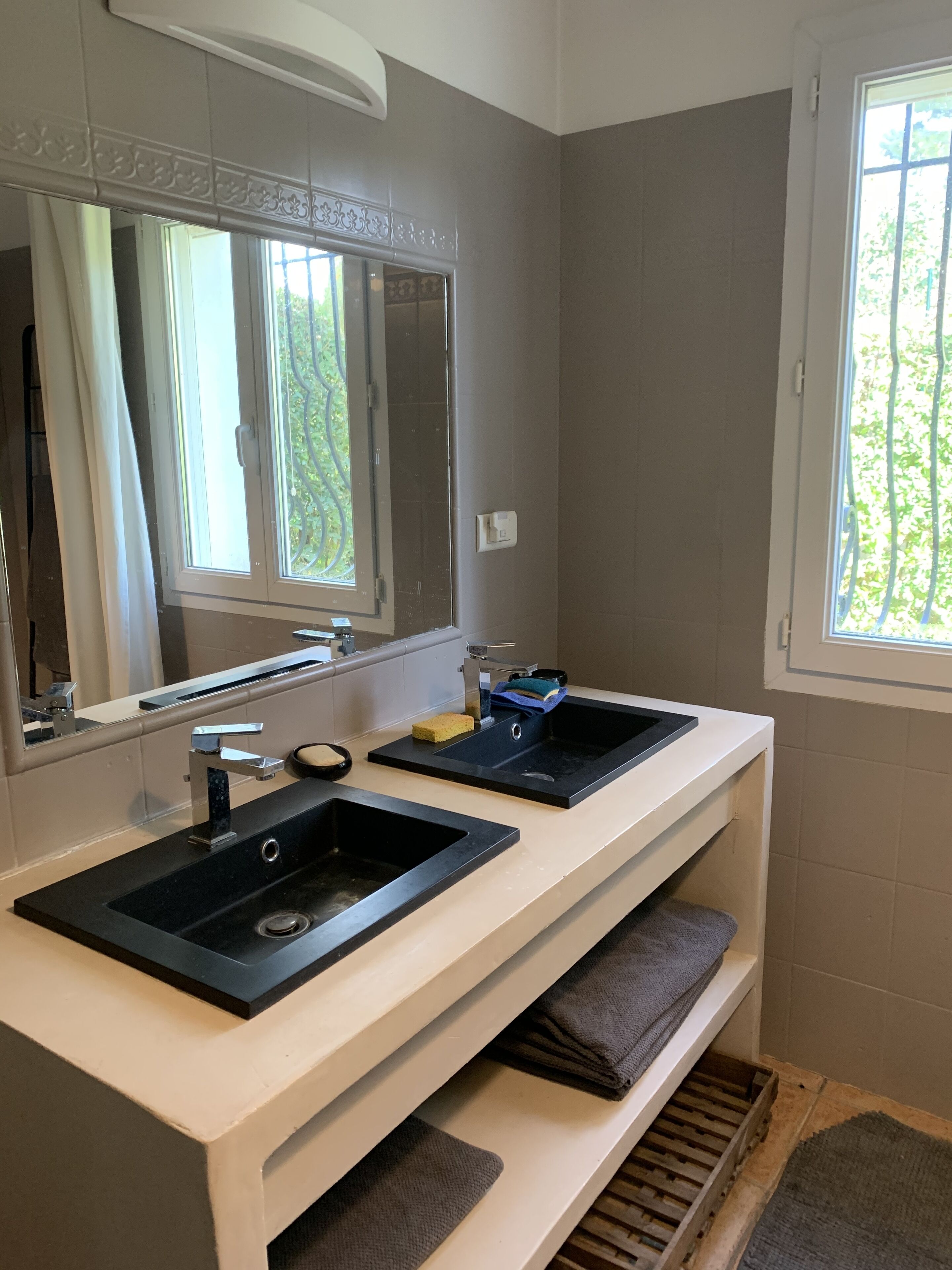 A bathroom with two sinks, a mirror, and a window.