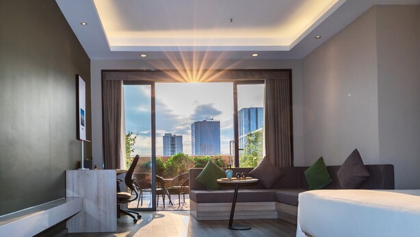 A modern hotel room with a large window, a sofa, a desk, and a chair. - Green Oriental Hotel (Shenzhen Pinghu South China City Hehua subway station) (Shenzhen)