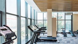 A gym with treadmills, a stationary bike, and a rowing machine. - Green Oriental Hotel (Shenzhen Pinghu South China City Hehua subway station) (Shenzhen)