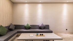 A modern living room with a sectional sofa, a coffee table, and a small side table. - Green Oriental Hotel (Shenzhen Pinghu South China City Hehua subway station) (Shenzhen)