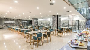 A spacious dining area with multiple tables and chairs, a marble wall, and a glass railing overlooking a lower level. - Green Oriental Hotel (Shenzhen Pinghu South China City Hehua subway station) (Shenzhen)