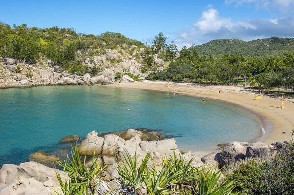 A beach with clear turquoise water, rocky shoreline, and lush greenery. - Alma Bay Holiday Unit 2-BOM (Arcadia)