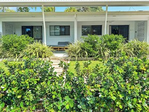 A modern building with a covered walkway, surrounded by lush greenery and a clear sky.