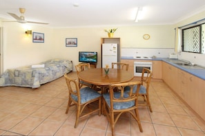 Un espace de vie compact comprenant un coin repas, une kitchenette et un lit.