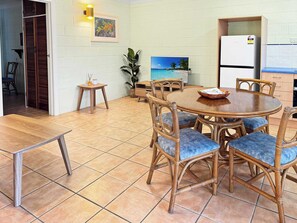 A dining area with a round table, wicker chairs, and a tiled floor.