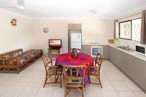 A compact living space with a dining area, kitchenette, and a sofa.