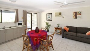 Un coin repas comprenant une table ronde, des chaises, un ventilateur de plafond et un canapé avec des coussins.