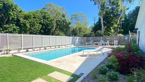 Un jardin avec une piscine, un espace clôturé et une terrasse avec des chaises.