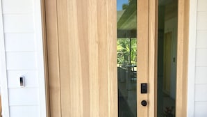 Una puerta de madera con un panel de vidrio, un felpudo y una planta en maceta.