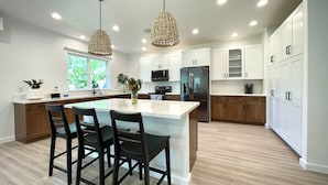 Una cocina moderna con una isla central, armarios blancos y un refrigerador de acero inoxidable.