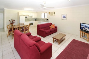 A living room with a sofa, a TV, and a dining area with chairs and a table.