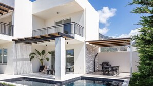 Une maison moderne à deux étages dotée d’une piscine, d’un espace salon extérieur et offrant une vue sur les montagnes.