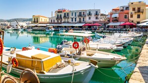 Un port de plaisance avec des bateaux amarrés, une promenade en bord de mer et des immeubles dotés de balcons.