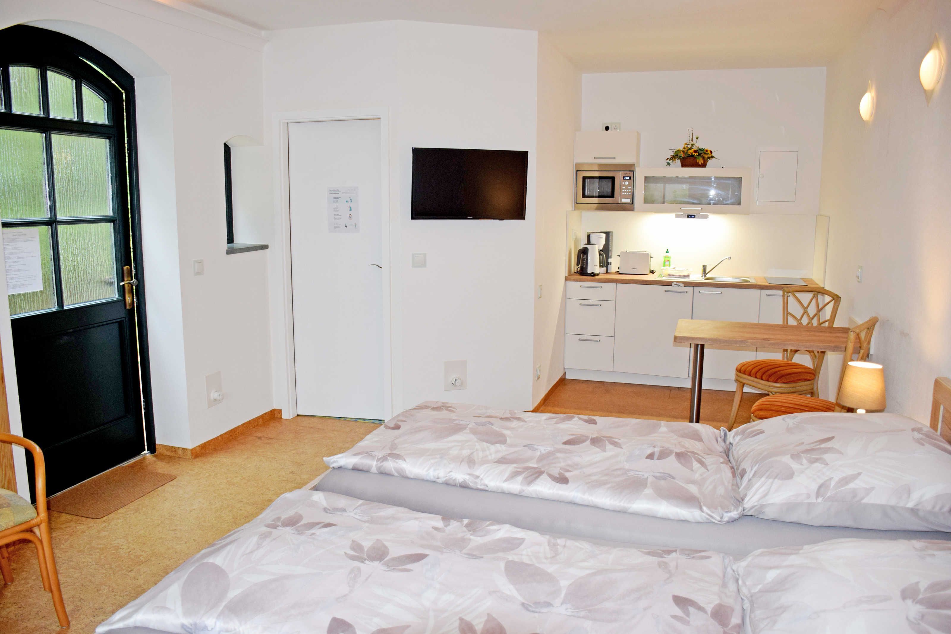 Ein kompaktes Hotelzimmer mit Bett, Schreibtisch, Mikrowelle und einer kleinen Küchenzeile.