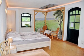 A bedroom with a bed, two chairs, a small table, and a window with a view of a landscape.