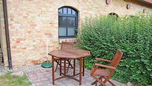 A brick building with a window, a table, and two chairs outside. - 08 holiday apartment with terrace - holiday farm on Rügen (Putbus)