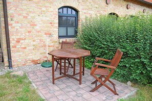 A brick building with a window, a table, and two chairs outside.