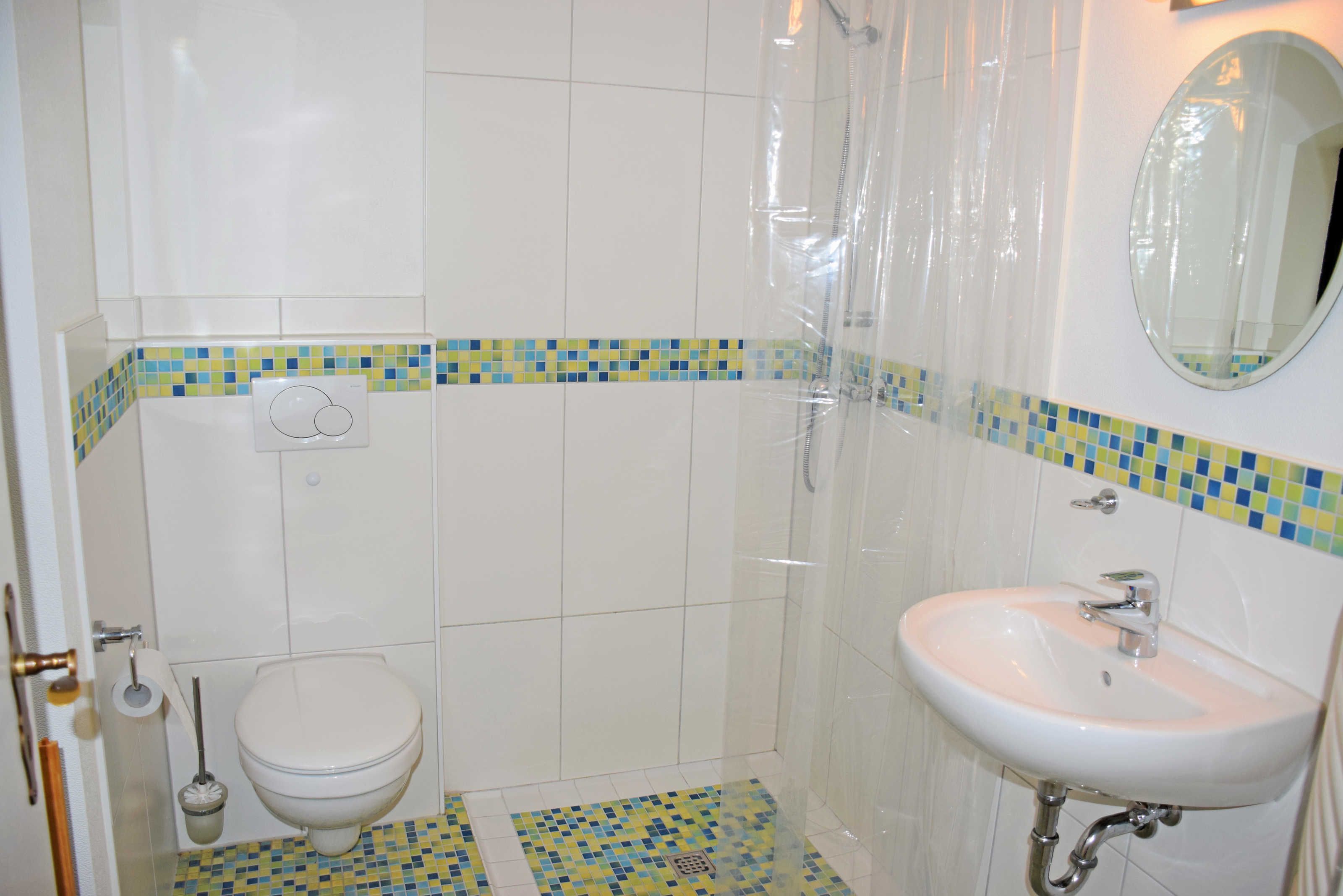Ein Badezimmer mit Toilette, Waschbecken, Dusche und Fliesenboden.