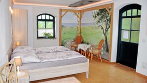 Une chambre à coucher comprenant un lit, deux chaises, une petite table et une fenêtre donnant sur un paysage.