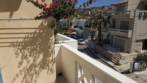 Una zona residenziale con un balcone, un'auto parcheggiata in strada e un edificio con un balcone.