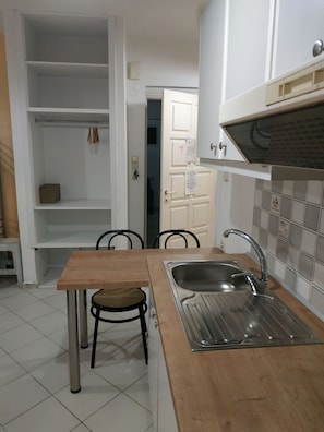 A kitchen with a wooden table, a chair, a sink, and cabinets. - Renia Studios Economy Studio Ground Floor (Malevizi)