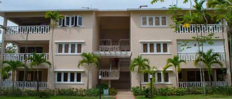 A multi-story hotel with balconies, a central courtyard, and surrounding greenery.